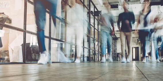 Multiracial young creative people in modern office. Successful hipster team in coworking. Businesspeople walking in the corridor of an business center. Motion blur.